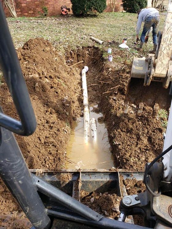 A man is digging a hole in the ground to install a pipe.